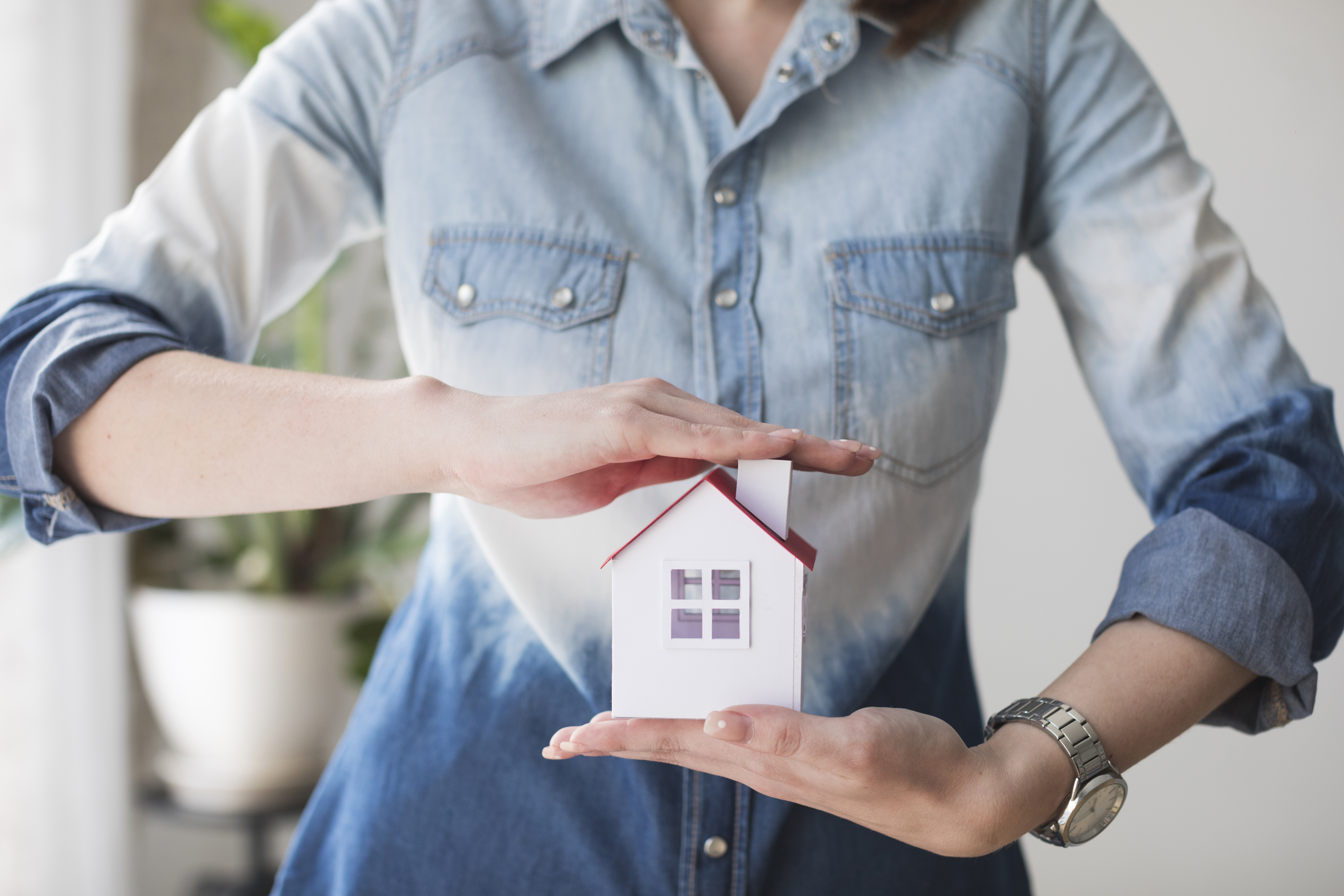 midsection-of-woman-protecting-house-model-at-office.jpg