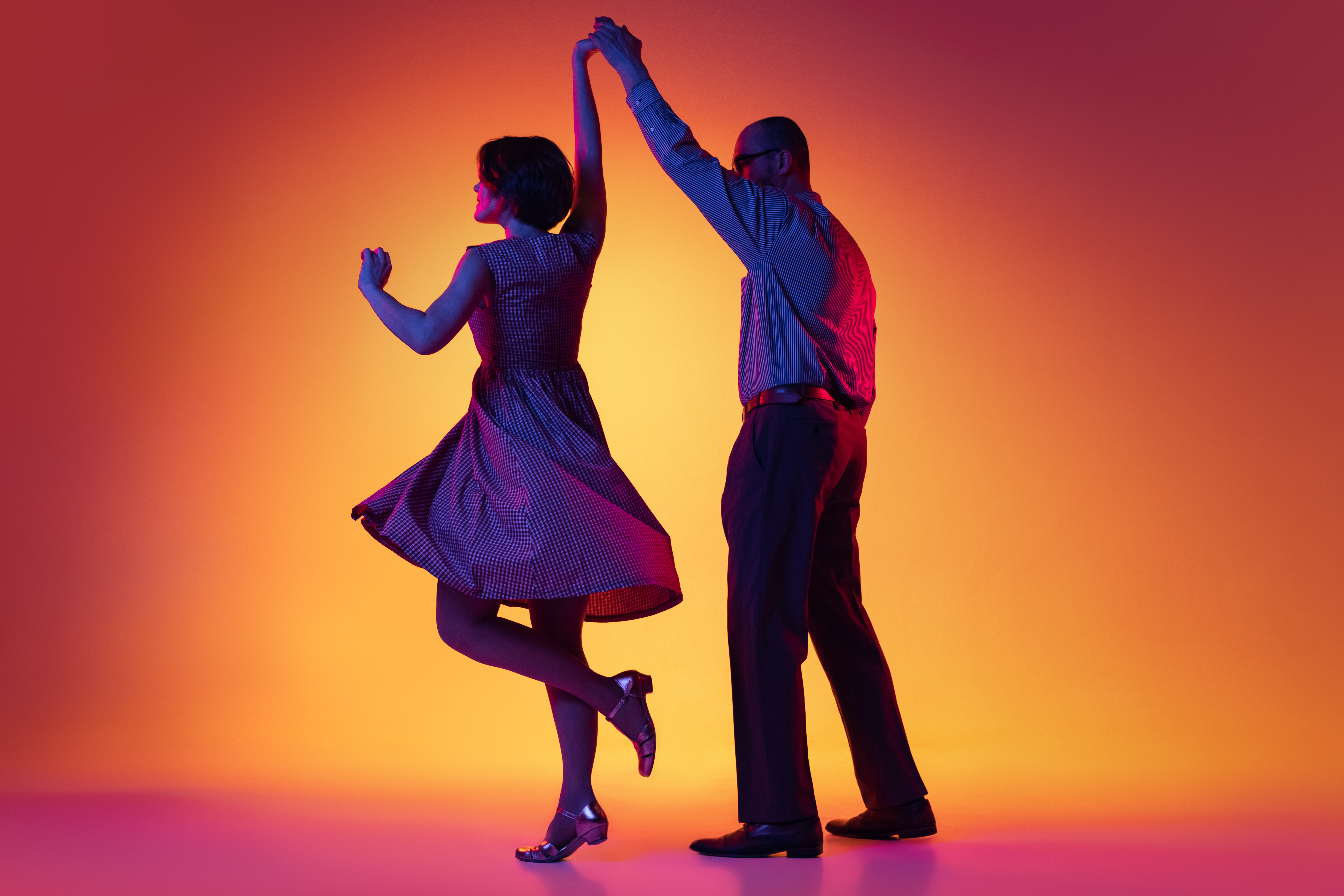 portrait-of-artistic-couple-dancing-retro-style-dance-isolated-over-gradient-orange-yellow-background-in-neon-light.jpg