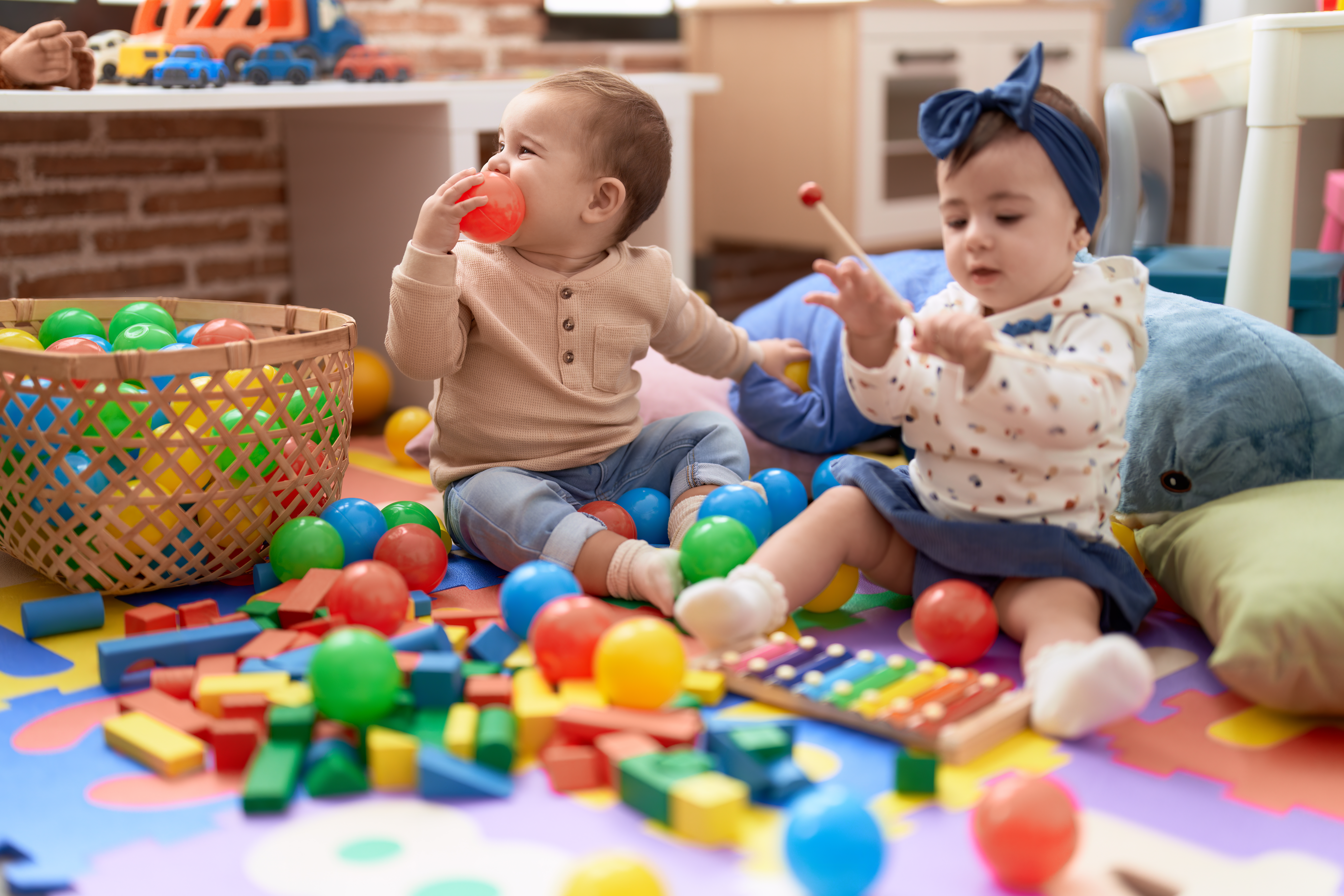 deux-bambins-jouant-avec-des-boules-et-xylophone-assis-sur-le-sol-a-la-maternelle.jpg